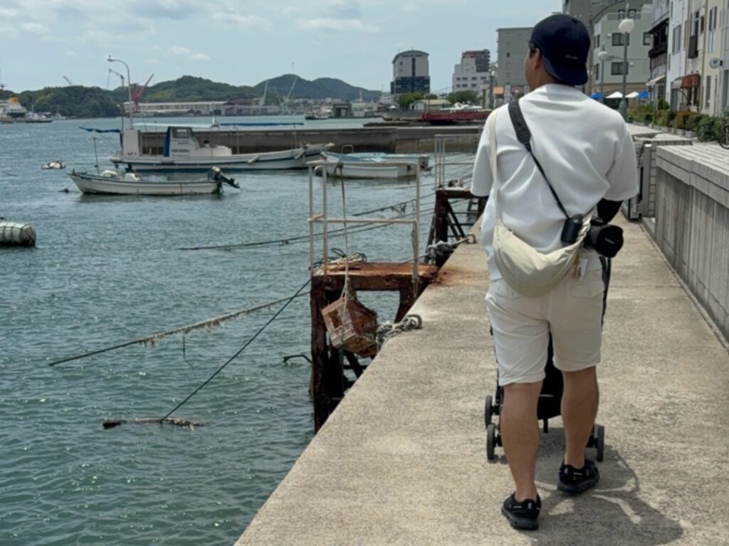 尾道水道沿いをベビーカーで駐車場へ戻る家族