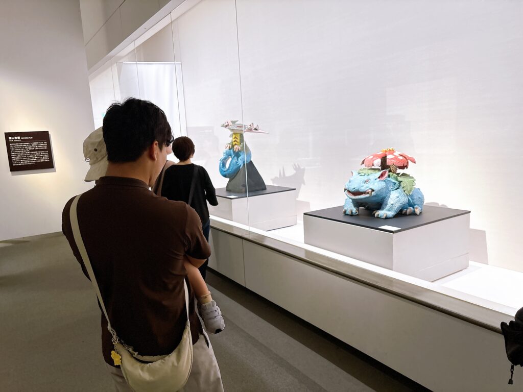 ポケモン工芸展の作品を見る2歳児と父親